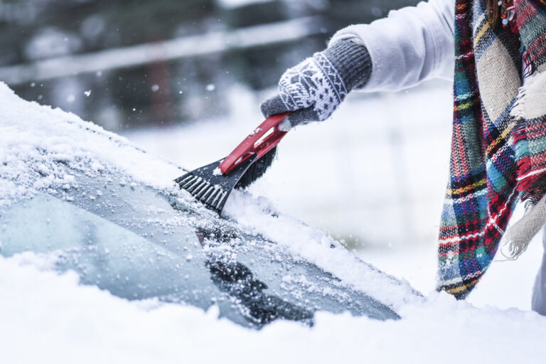 Woman cleaning snow from windshield