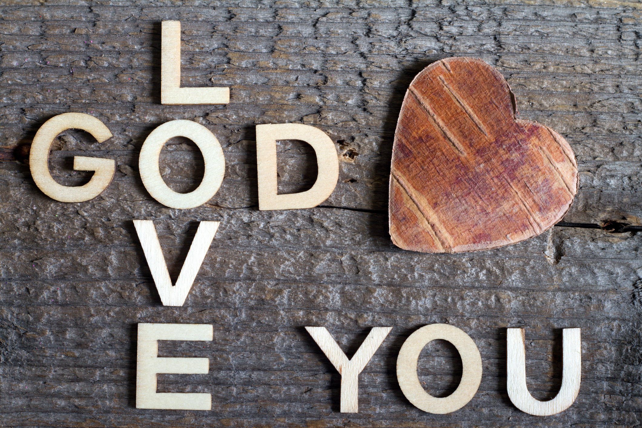 God is love letters with cross and heart religion concept on wooden background closeup